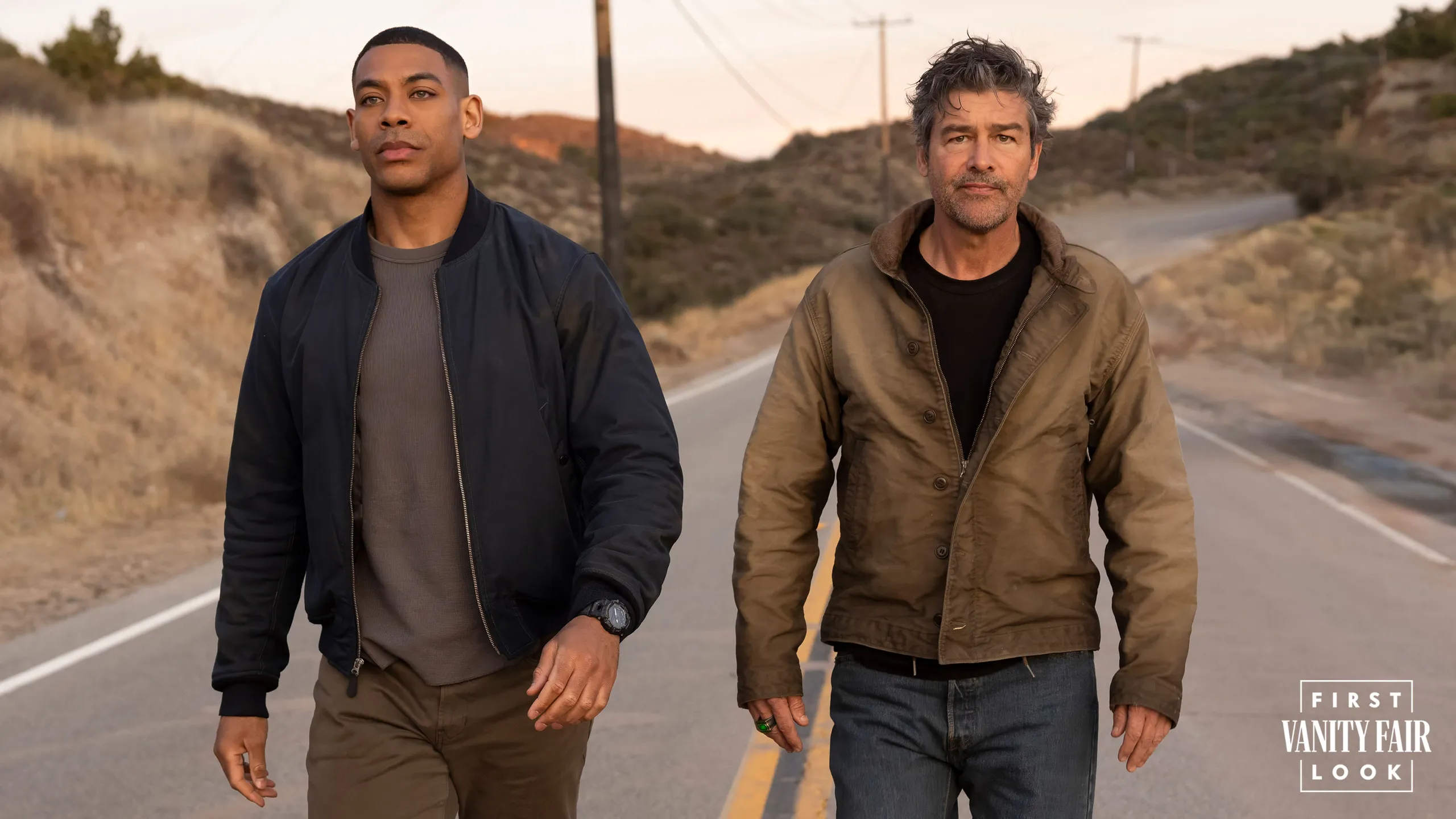 Aaron Pierre and Kyle Chandler walking down a rural road in a Vanity Fair first look photo for Lanterns
